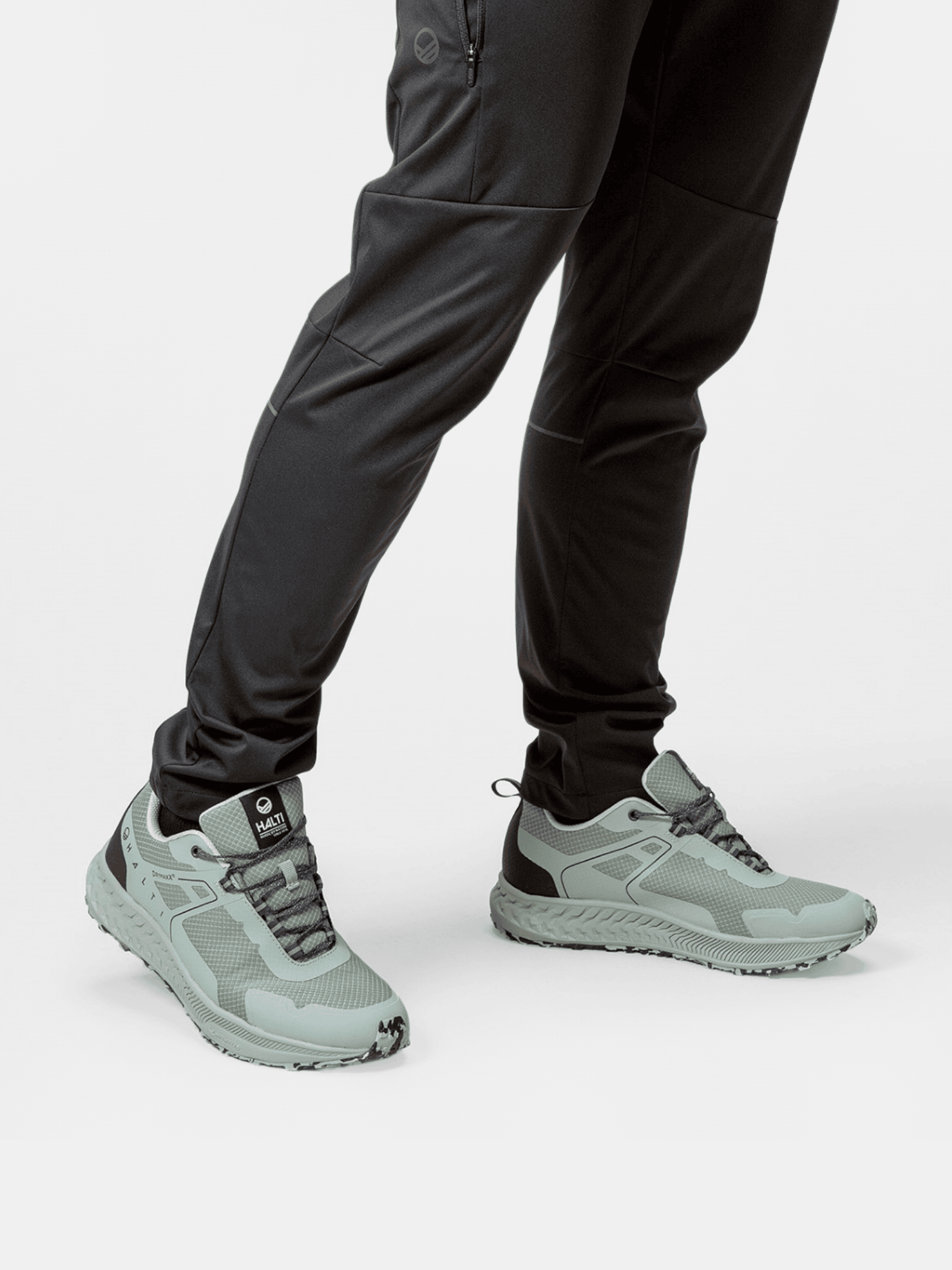 Person wearing Halti Pallas Low 2 DrymaxX Hybrid Sneaker Mens in light gray mesh with black pants on a white background.