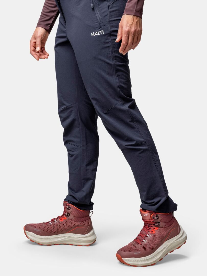 Woman wearing Halti Rapid DX Mid outdoor shoes in maroon with dark pants, standing against a white background.