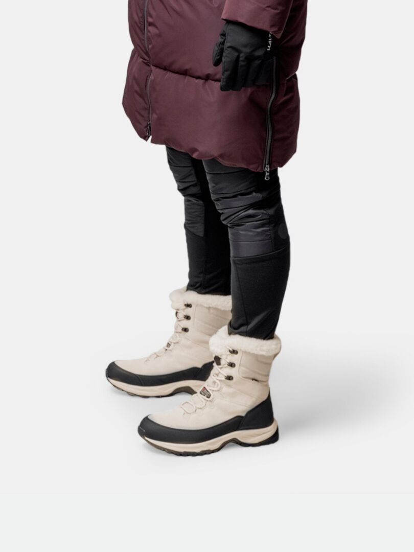 A person in a maroon coat and black gloves wears Halti Tornio 2 DX Winterboots with a GripmaxX Arctic outsole.