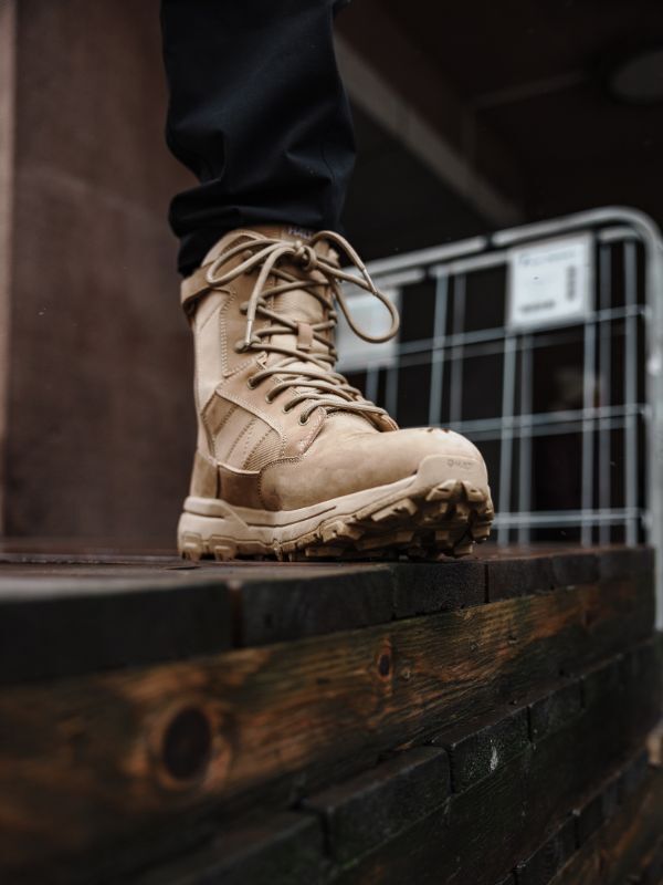 Close-up of Halti's Regis DX Boot Men's, waterproof leather hiking boots, on a wet wood surface near a metal fence.