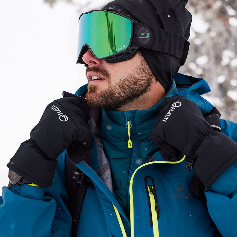 Man in a Halti Alpine Unisex 3L DrymaxX Shell Jacket and goggles stands in the snow, adjusting his gloves.