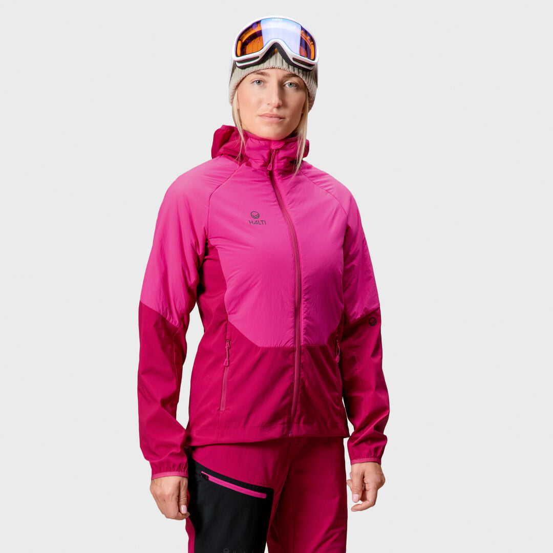 A woman in the Halti Crust Womens Layer Jacket and ski goggles stands against a plain light background.