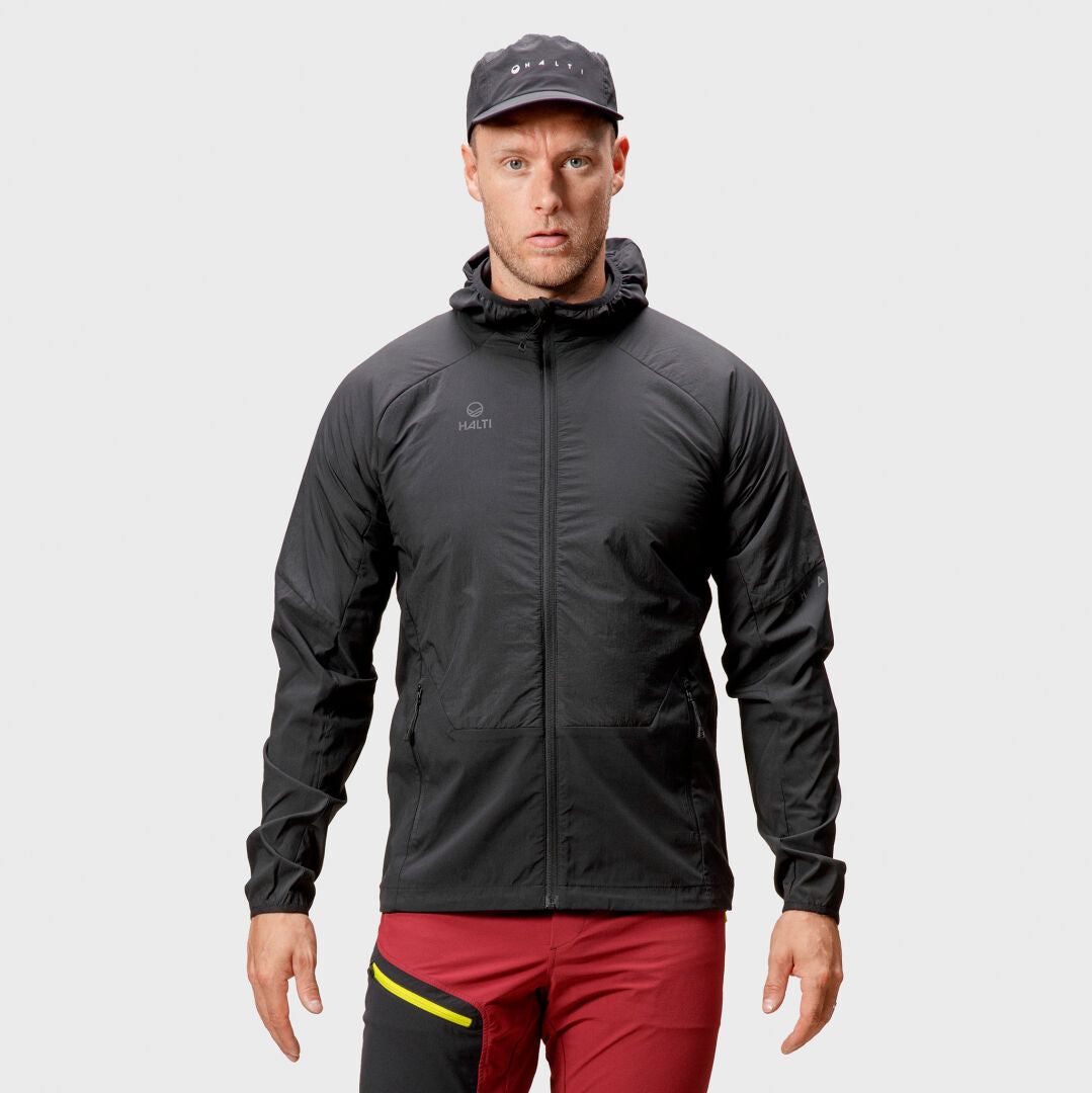 A man in the Halti Crust Mens Layer Jacket and red pants with black and yellow accents stands ready for winter sports.