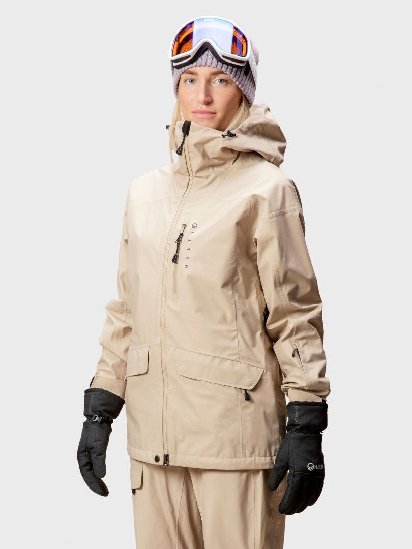 A woman wears the Halti Settler 3L DrymaxX Ski Jacket, matching pants, gloves, and goggles against a plain background.