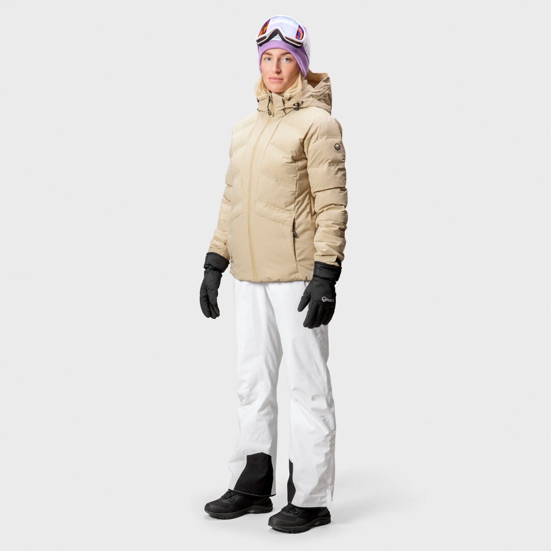 Woman wearing the Halti Nordic Arcty Ski Jacket, white snow pants, black gloves, and ski goggles.