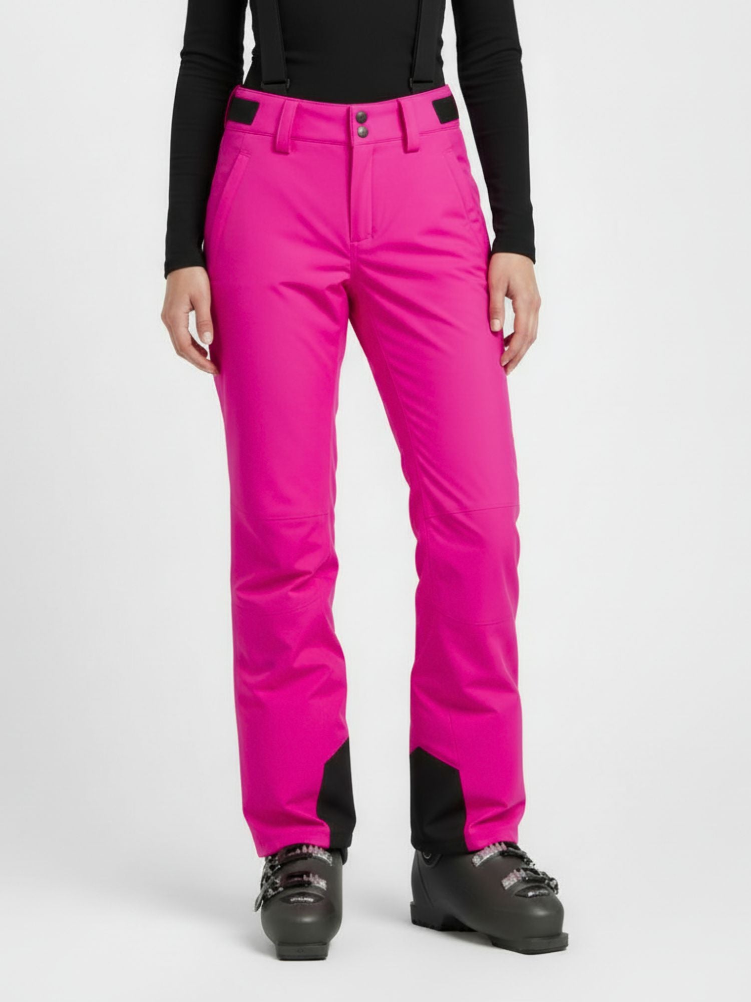Woman in Halti Trusty DrymaxX Ski Pants (pink) with black suspenders, black top, and ski boots, shown shoulders down.