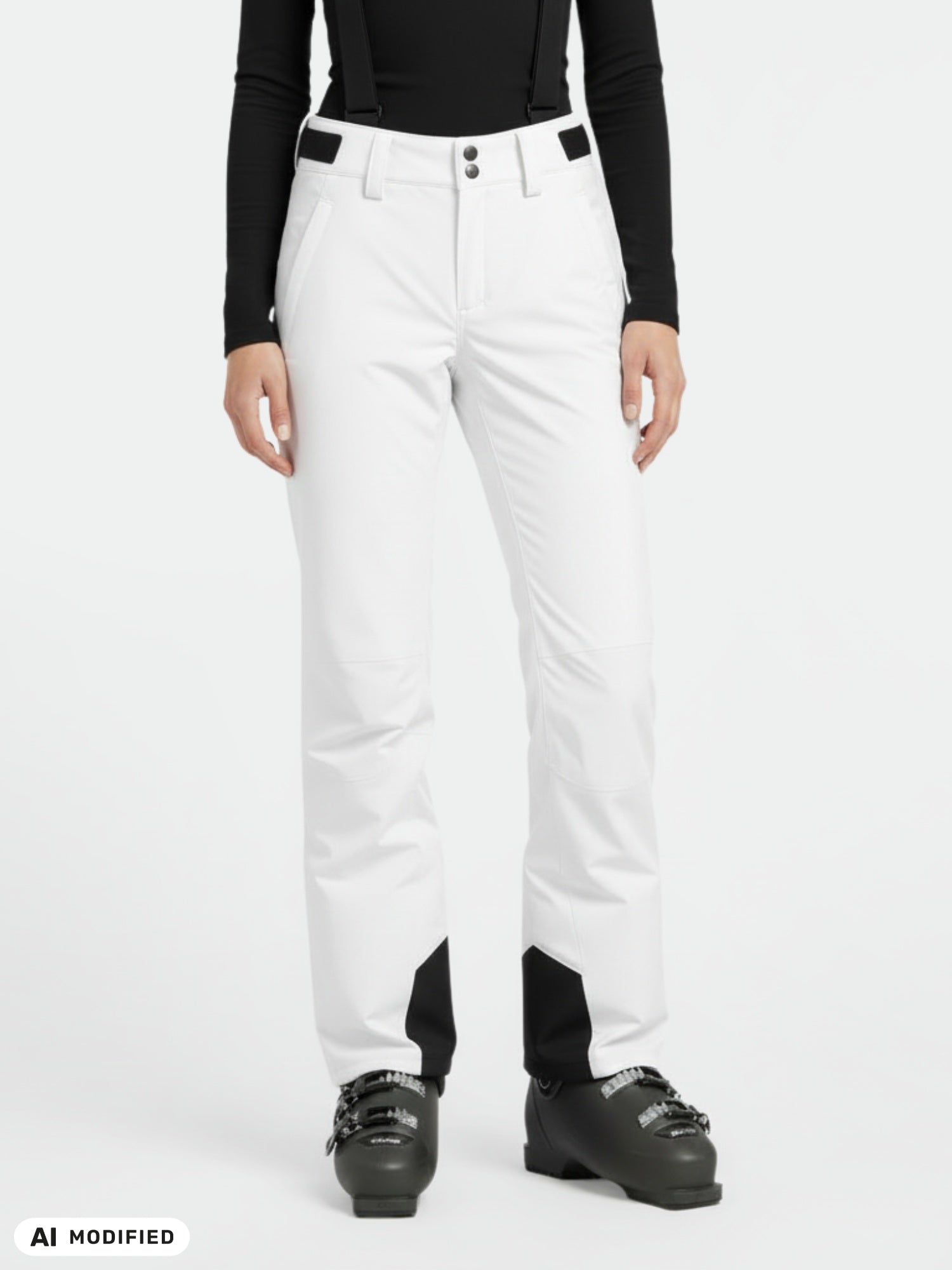 Woman wearing Halti Trusty DX Ski Pants with suspenders, black long-sleeve top, and ski boots against a white background.