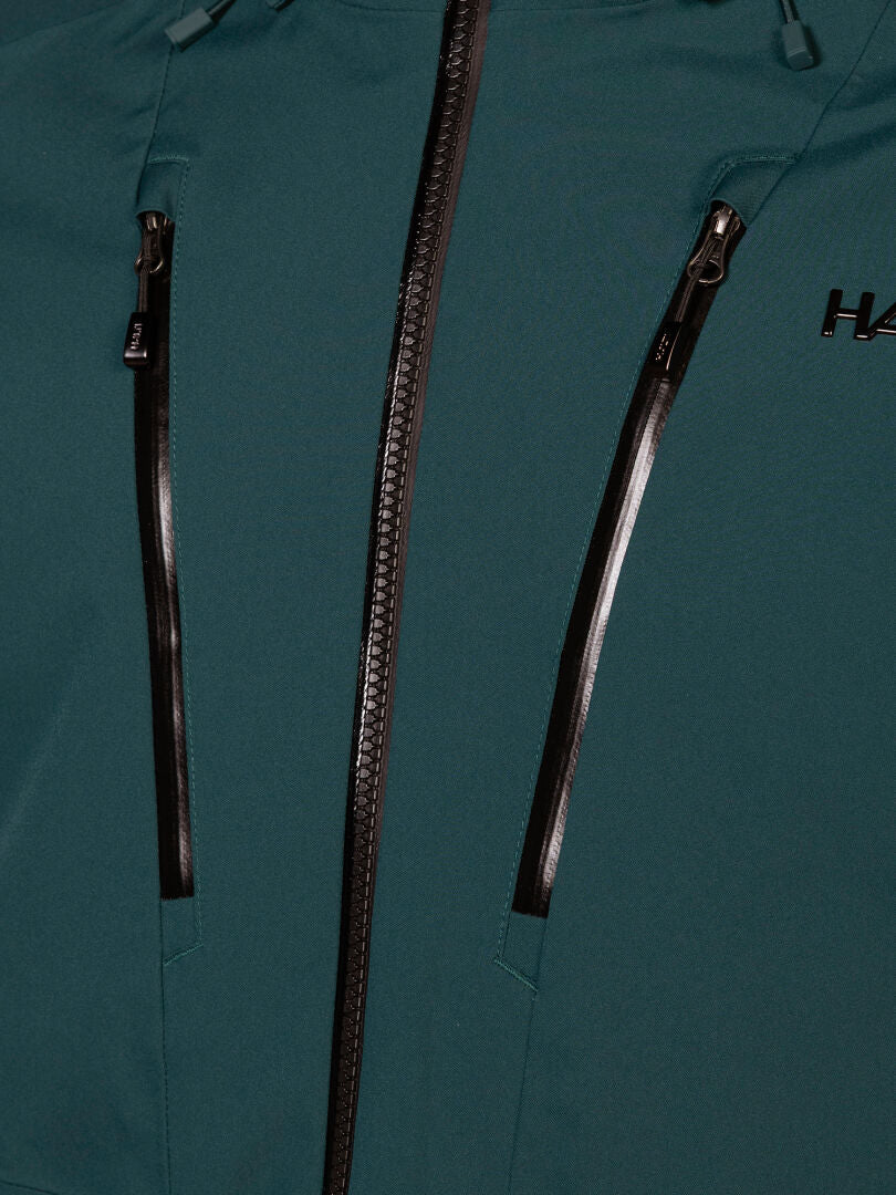 Close-up of a teal Halti Vertica DX Ski Jacket Men’s featuring a waterproof zip and sealed vertical chest pockets.