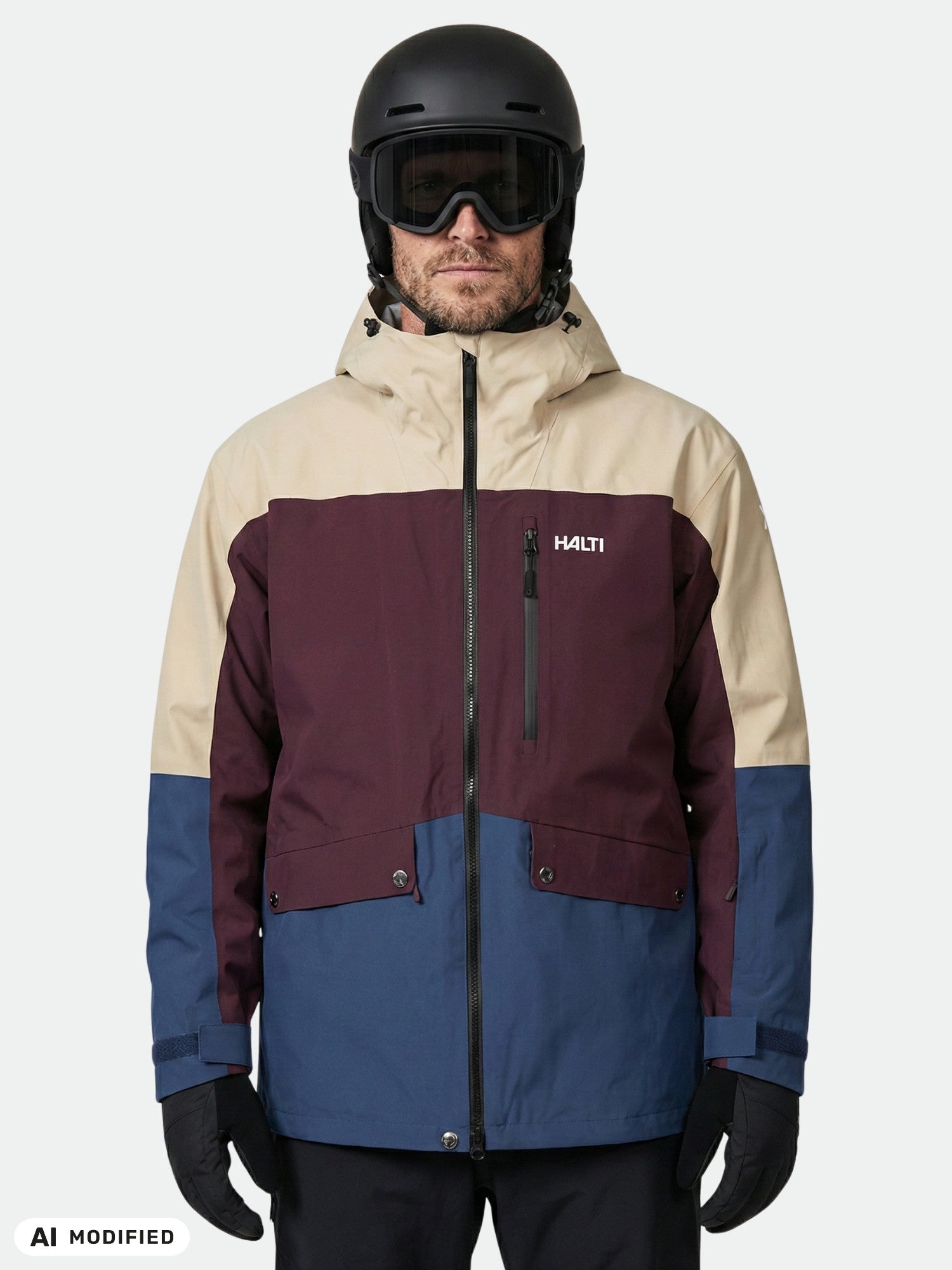 Person in a beige, maroon, and blue Halti Settler 3L DX Ski Jacket, black helmet, goggles, and gloves.