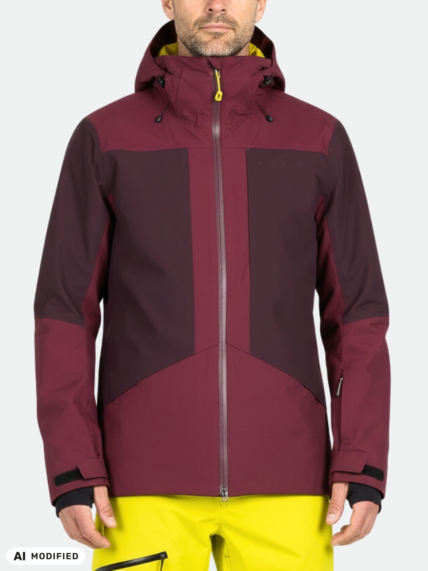 A person wears a maroon Halti Planker DX Ski Jacket with yellow zippers and bright yellow pants against a plain background.