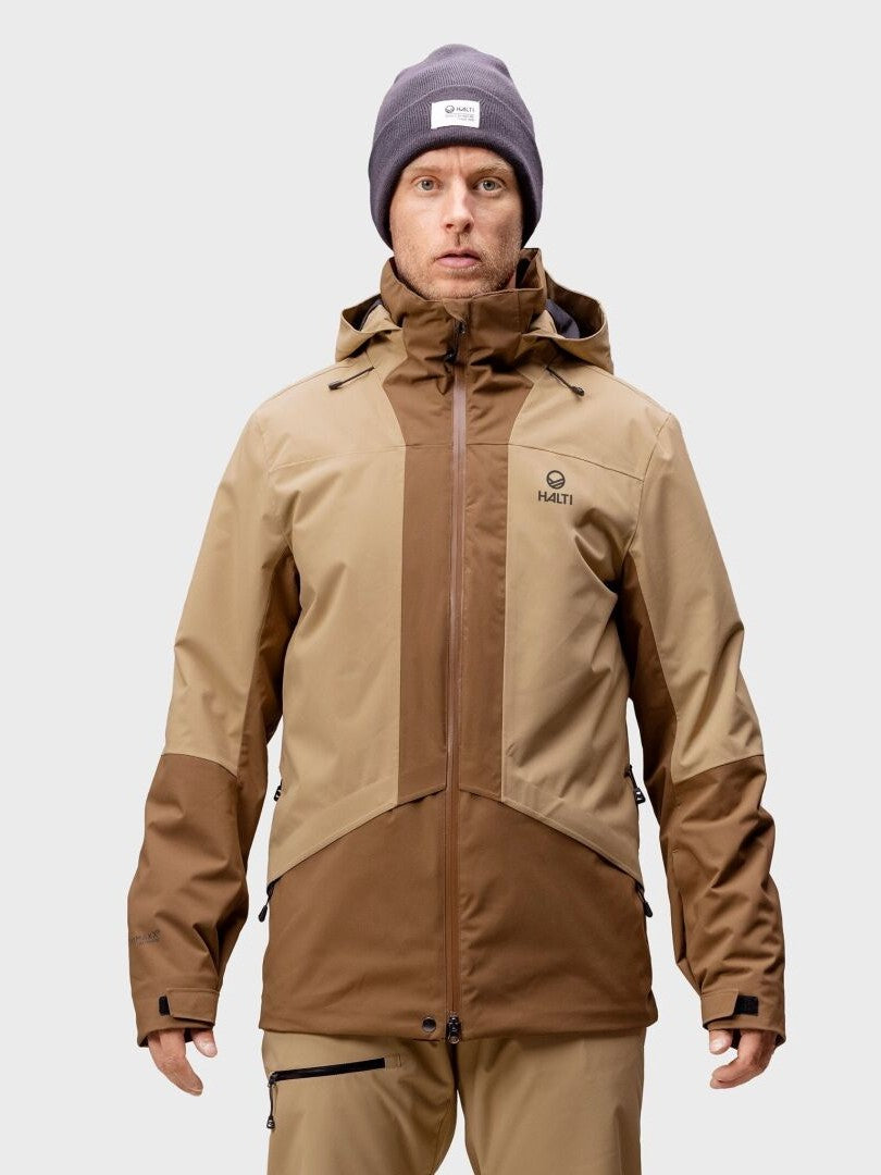 A person wears the Halti Planker DrymaxX Men's Ski Jacket in brown and tan with beige pants, facing forward.
