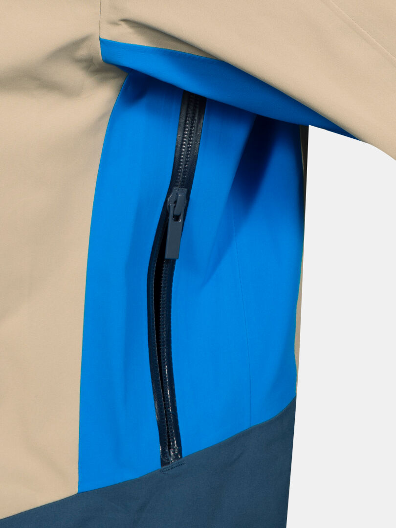 Close-up of the Halti Rizle 3L DX Ski Jacket Unisex in beige, blue, and dark blue with a side vertical zip pocket.