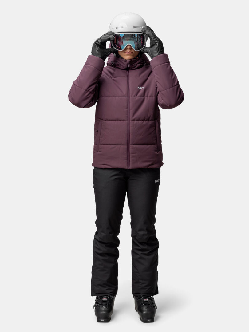 Woman facing forward in Halti Ascale Puffer Ski Jacket, black snow pants, ski boots, gloves, helmet, and goggles.