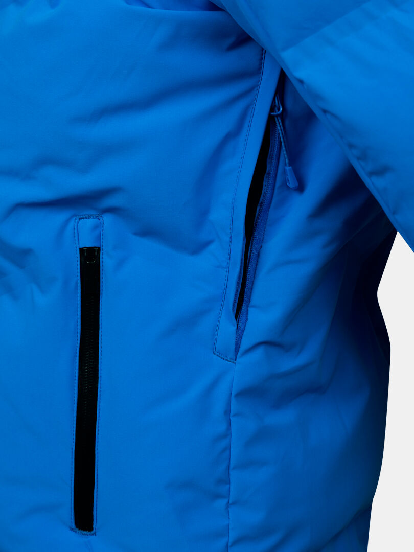 Close-up of Halti Nordic Arcty II Men's Ski Jacket in bright blue with black zippers on vertical and angled zip pockets.