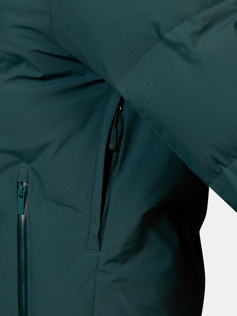 Close-up of a dark teal Nordic Arcty II Ski Jacket Men’s featuring a zippered side pocket.
