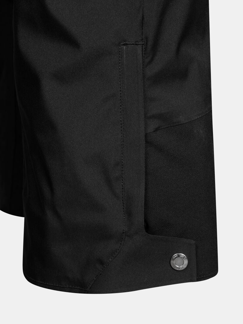 Close-up of black waterproof Vertica II DX Ski Pants Men’s with a reinforced panel and metal snap button at the hem.
