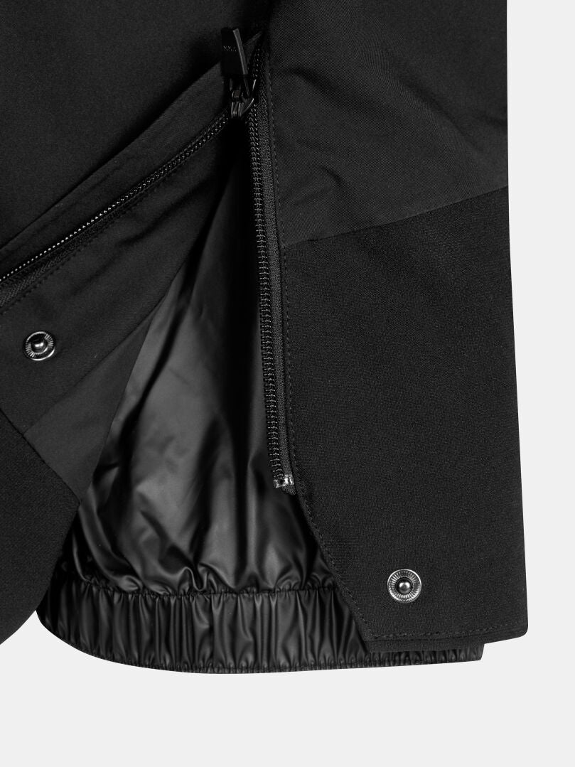 Close-up of a Vertica II DX Ski Pants Men’s leg hem featuring a side zipper, snap button, and inner snow gaiter.