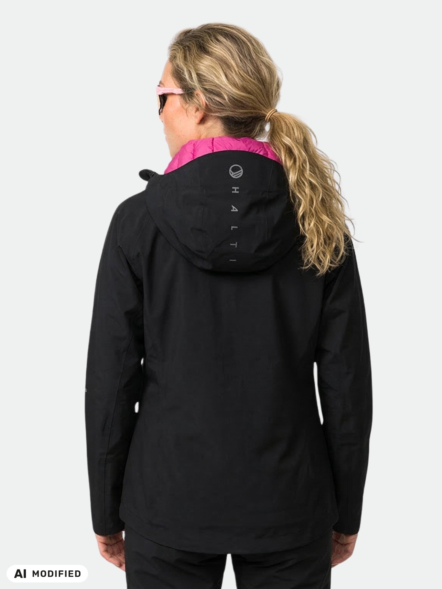 Blonde-haired woman in ponytail wears Halti Kaarna DX 3L Shell Jacket, black with pink hood lining, seen from behind.