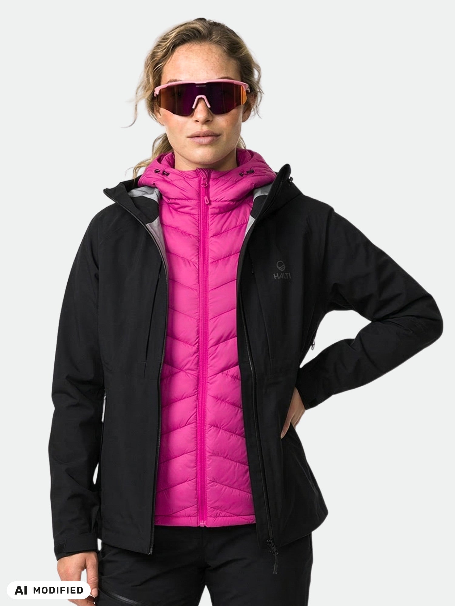 Model wears the Halti Kaarna DX 3L Shell Jacket over a pink puffer and large sunglasses, against a plain background.