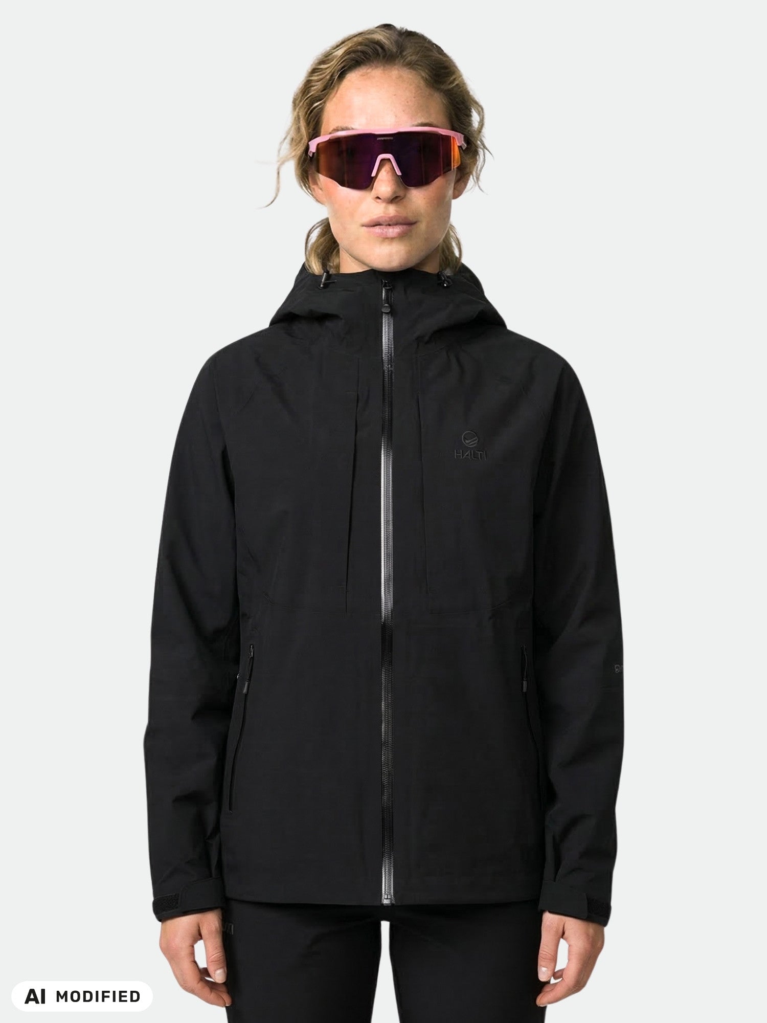 A person wears the Halti Kaarna DX 3L Shell Jacket Women's and pink sunglasses against a plain light background.
