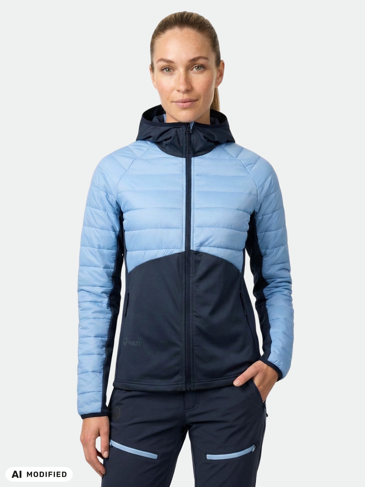 A woman wears the Halti Veidnes Women's Insulation Jacket and navy pants against a plain background.