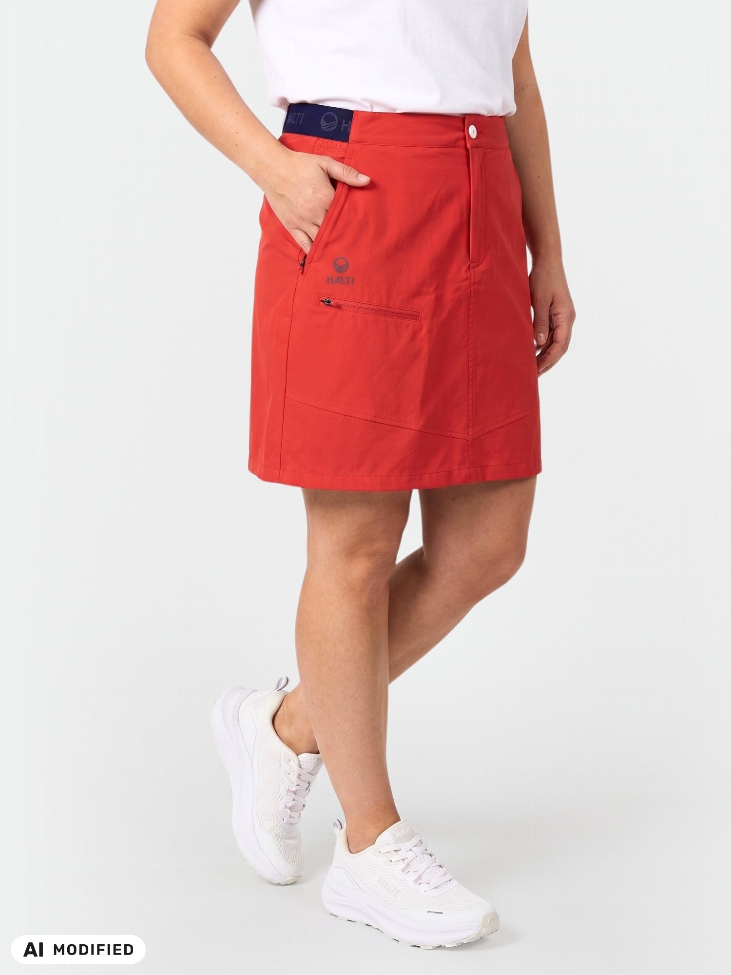 A person wears a Halti Pallas Lite X-stretch Skort in red with pockets and white sneakers, featuring Quick Dry material.