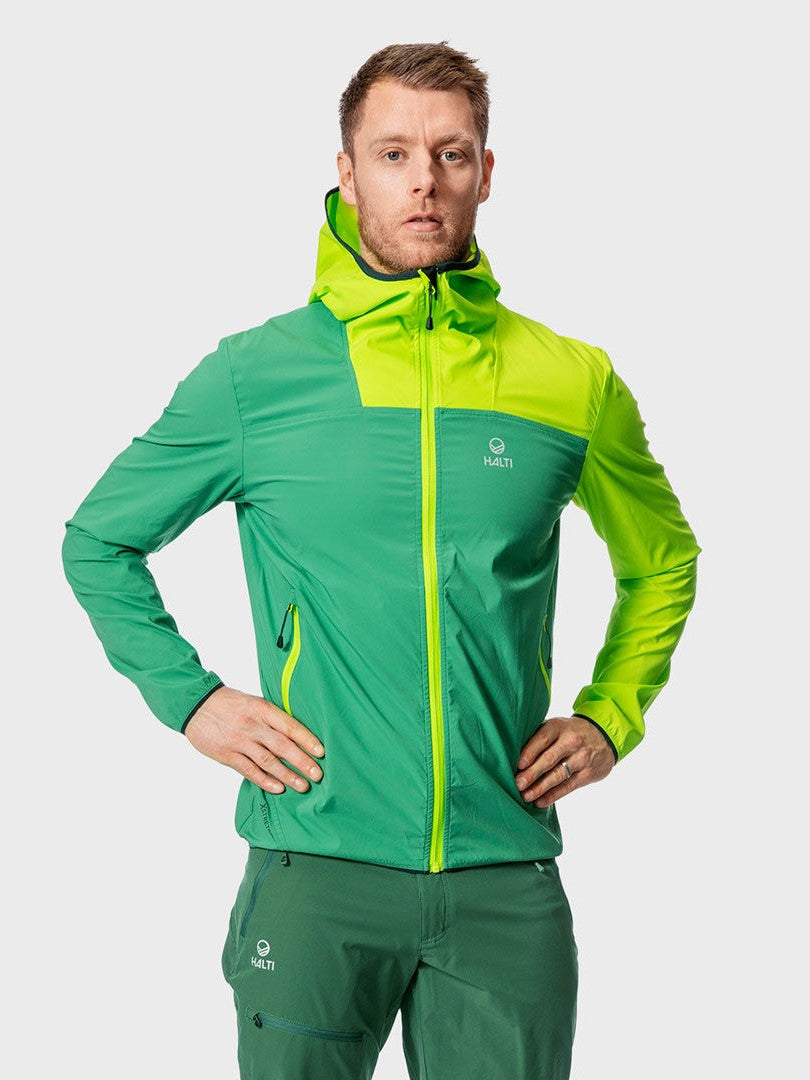 A man with hands on hips wears a green Halti Pallas Mens Lite X-stretch jacket and matching breathable pants.