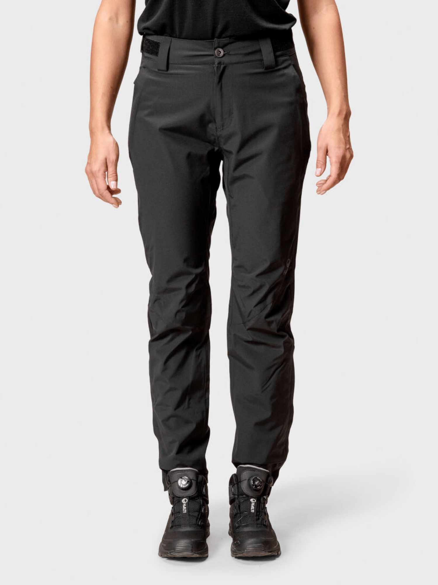 Model wearing Halti Juonto Womens Shell Pants and black athletic shoes, shown from shoulders to feet against a plain backdrop.