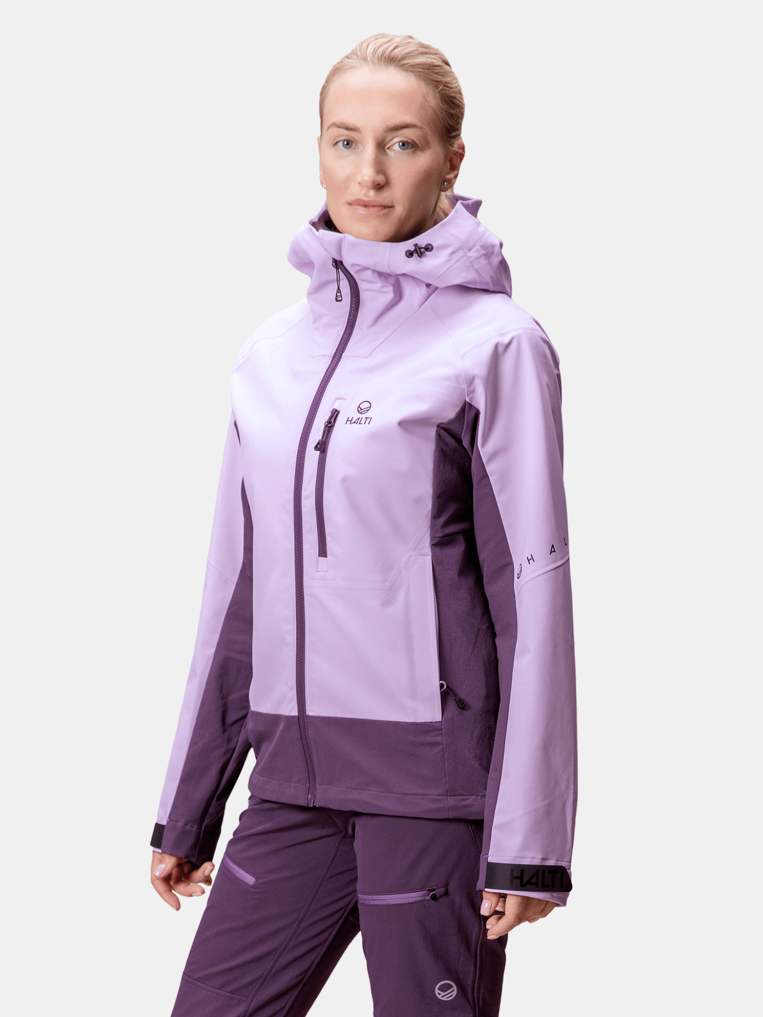 A woman models the Halti Pallas III Women's Warm Hybrid Jacket and matching purple pants against a plain background.