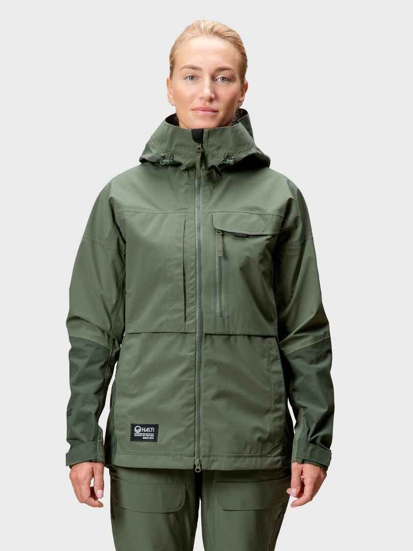 A woman wears a green Halti Hiker Drymaxx 3L Ventilated Jacket and pants, facing forward against a plain background.