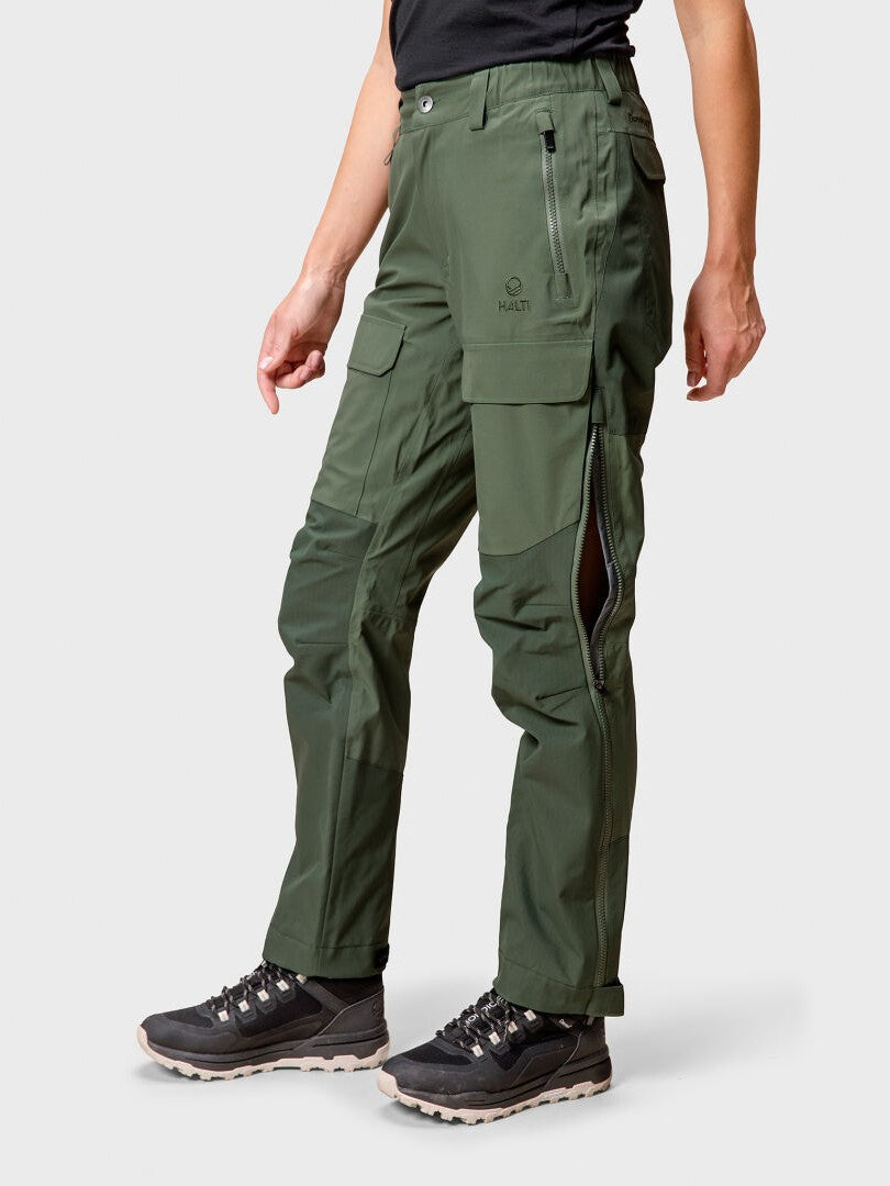 A person wears Halti Hiker DrymaxX 3L Ventilated Pants Womens, a black shirt, and black hiking shoes on a white background.