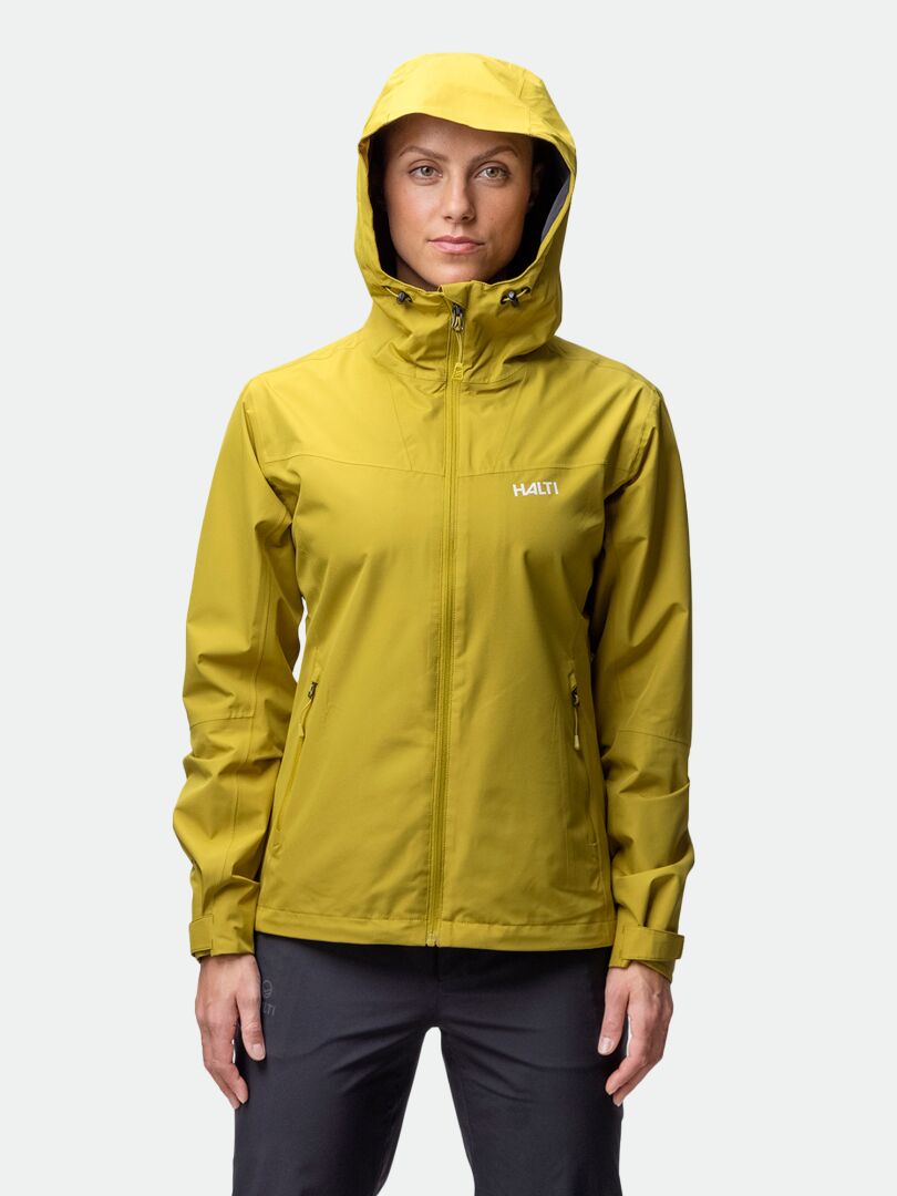 A person wears a yellow Halti Forter DX Shell Jacket for women and black pants, standing forward against a plain background.