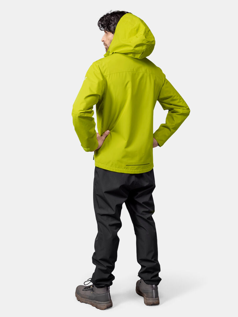 A person in a bright green Halti Forter DX Shell Jacket and black pants stands facing away, hands on hips.