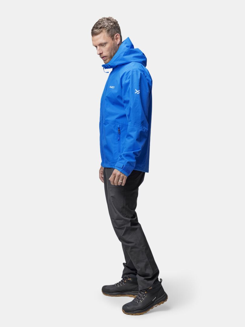 Man wearing Halti Forter DX Shell Jacket, dark pants, and black hiking boots stands against a white background.