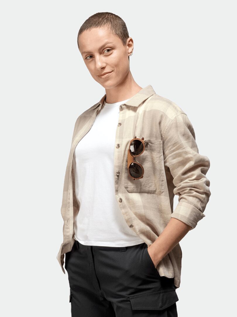 Woman with short hair in Halti Hiker Trekking Shirt, white tee & black pants; shades in pocket—outdoor-ready.