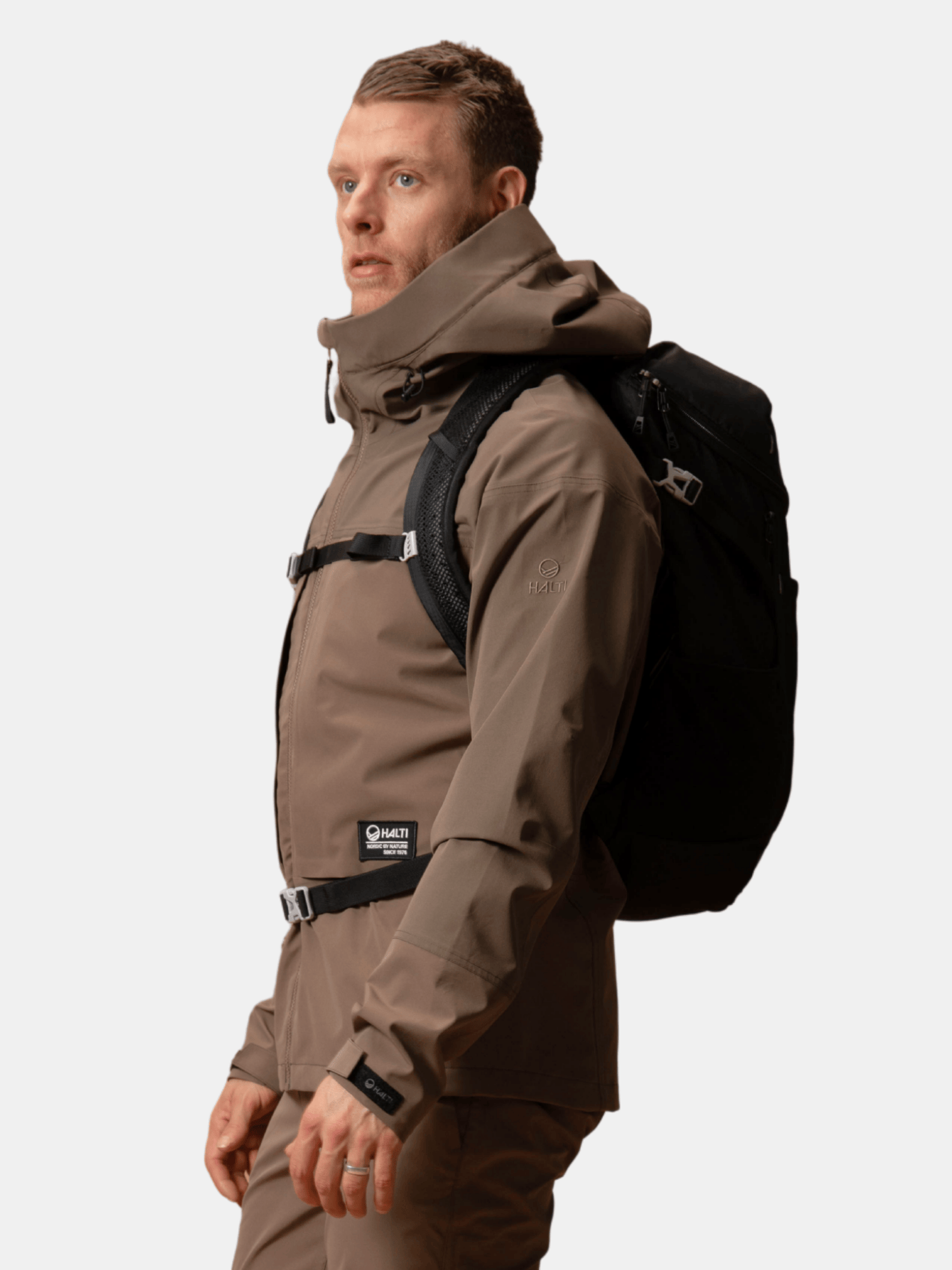 A man in a Halti Hiker II DrymaxX Shell Jacket and black backpack stands against a plain light background.