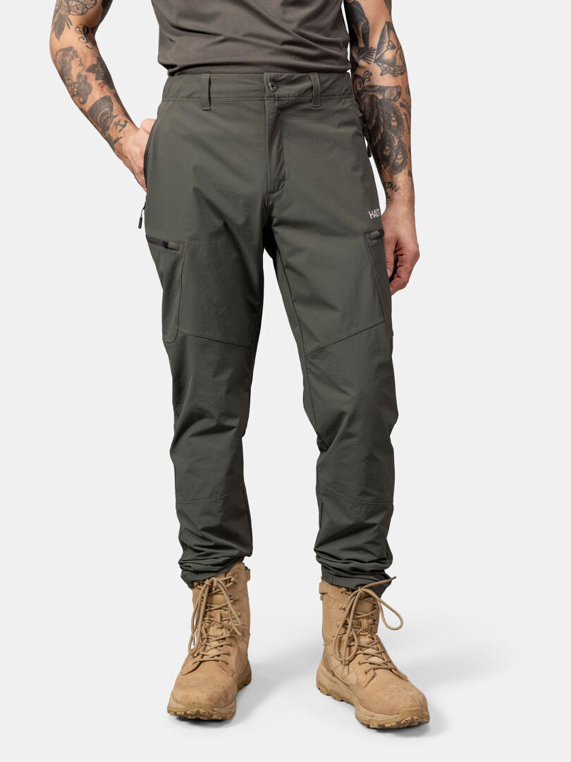 Person wearing Halti Pallas Evo X-stretch Pants, hands in pockets, stands against a plain white background.