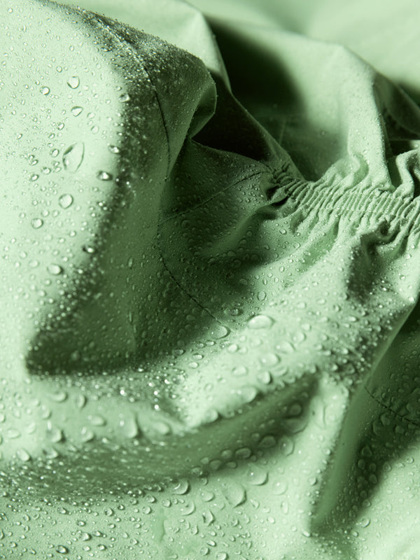 Close-up of Halti Pisarat 2,5L DX Shell Jacket Womens in light green, showing its water-resistant texture and stitching.