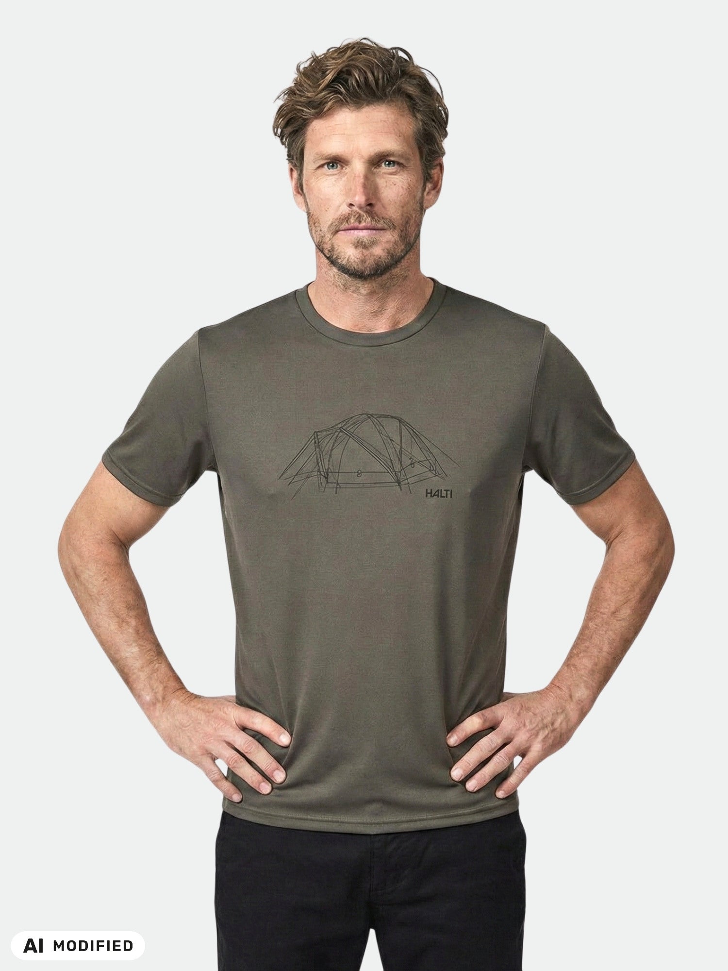A man wears the Halti Kalteva T-shirt—gray, with a tent line drawing—standing hands-on-hips against a plain background.