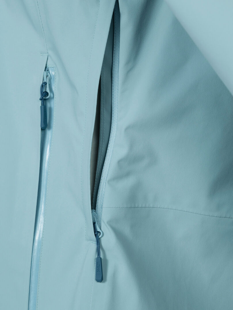 Close-up of Halti Staala DX Shell Jacket Women's in light blue with two vertical zip pockets and water-repellent fabric.