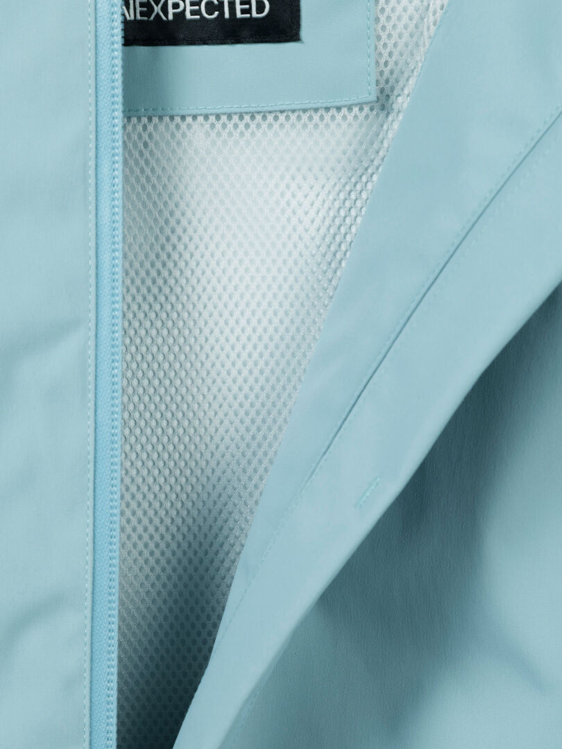 Close-up of Halti Staala DX Shell Jacket Women's in light blue with mesh lining and partial black label with white text.