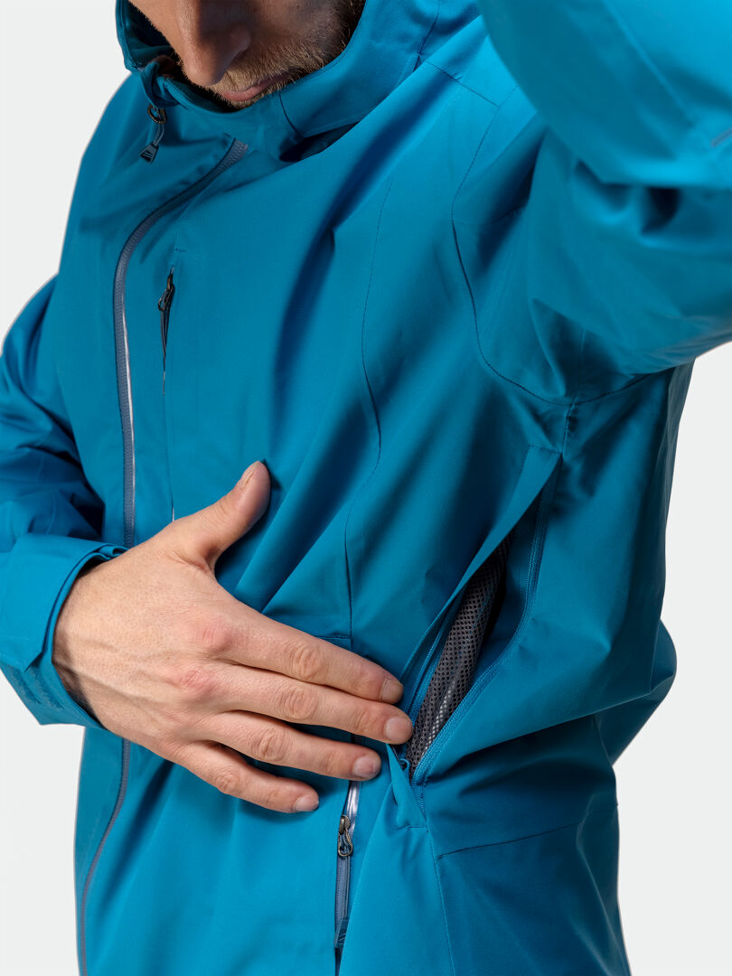 Person unzipping the side vent on the Halti Staala DX Shell Jacket Mens, a technical jacket for outdoor adventures.