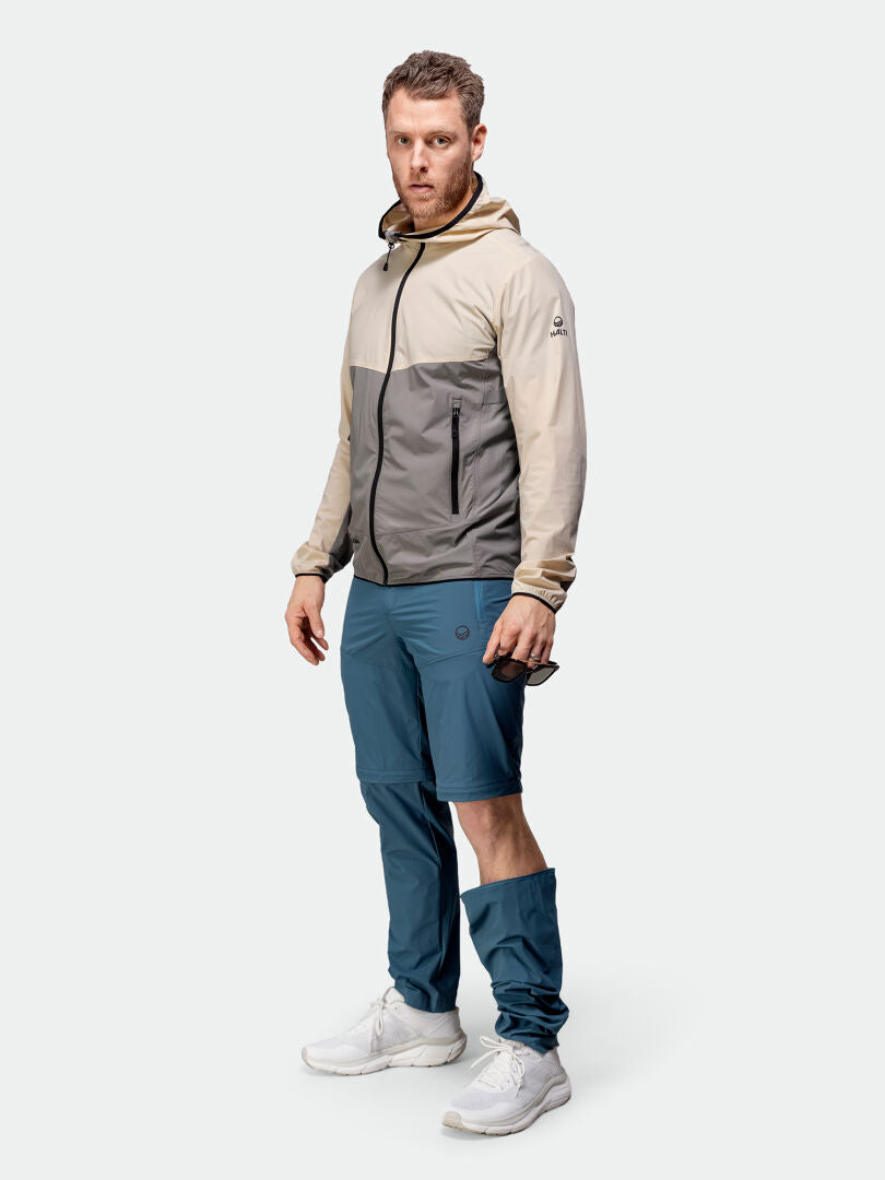 A man wears the Halti Pallas Cool X-stretch Jacket and blue UPF 90+ convertible pants against a plain background.