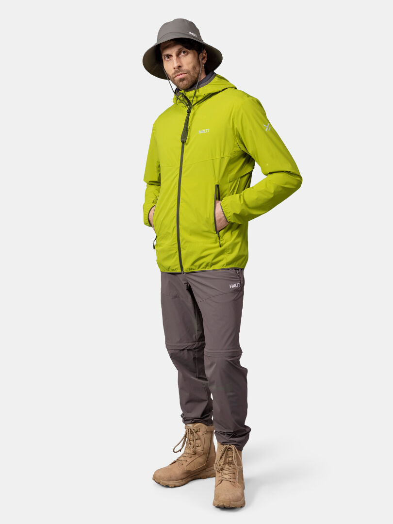 A man in a green Halti Pallas Cool X-stretch Jacket, gray pants, tan boots, and a wide-brim hat faces the camera.