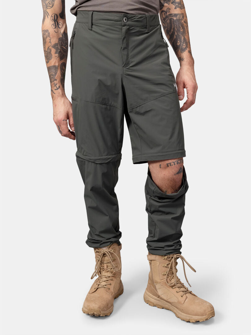 Man wearing Halti Pallas Cool Stretch Zip-off Pants with one leg unzipped, tan boots, and tattoos on arms and leg.