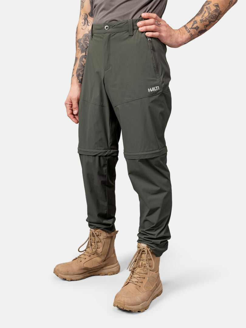 Man wearing Halti Pallas Cool Stretch Zip-off Pants, tan boots, and a gray shirt against a white background.