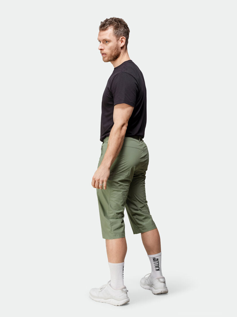 Man wearing Halti Pallas Cool X-stretch Capri Pants, black moisture-wicking t-shirt, white socks and sneakers.