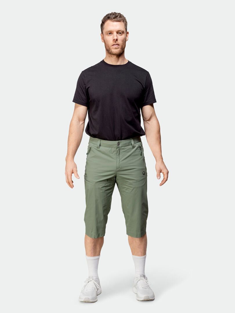 A man wears Halti Pallas Cool X-stretch Capri Pants, a moisture-wicking black t-shirt, white socks, and white sneakers.