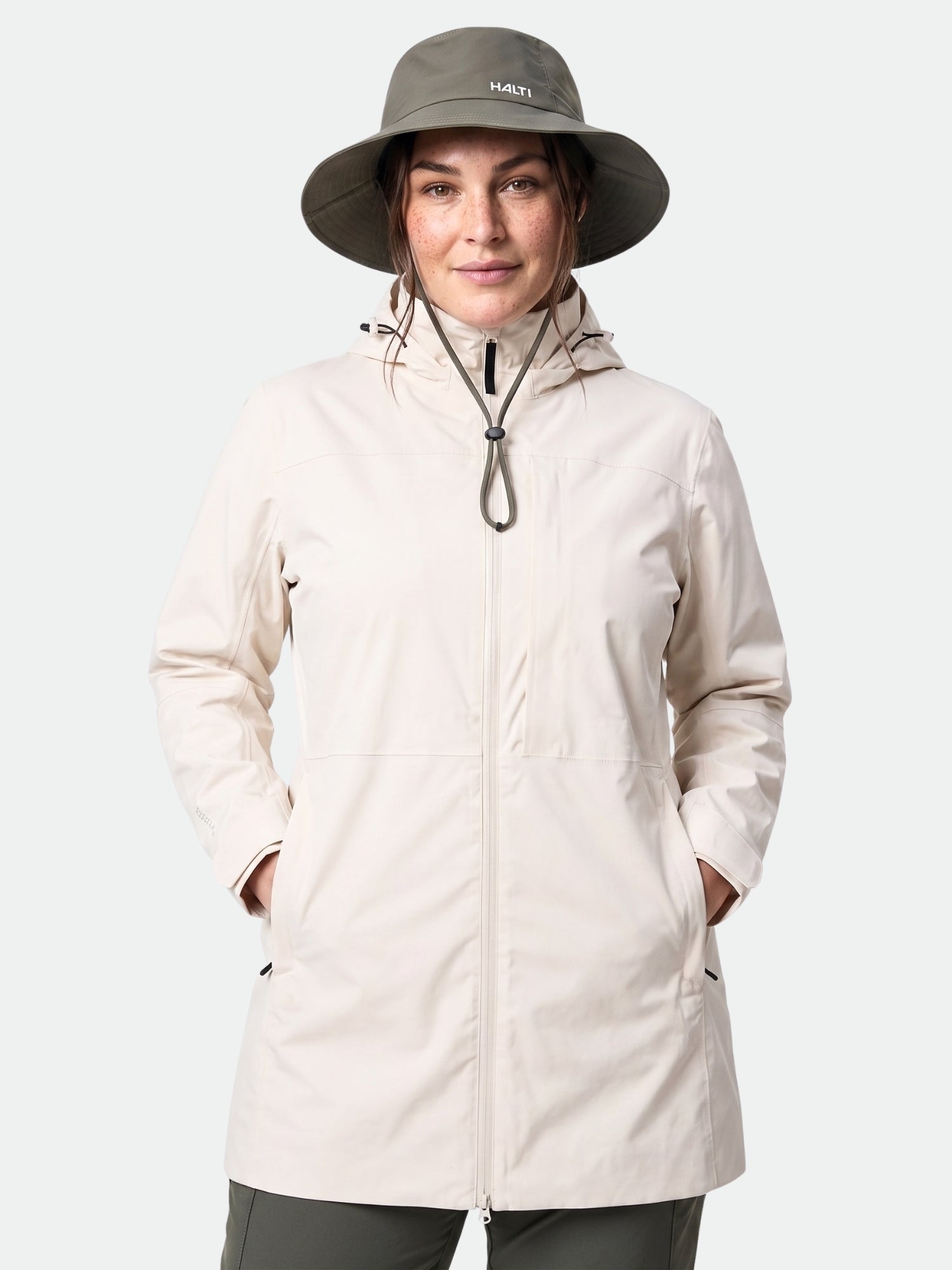 A woman faces forward with hands in pockets, wearing the Halti Kallas DX Parka Jacket Plus featuring DrymaxX.