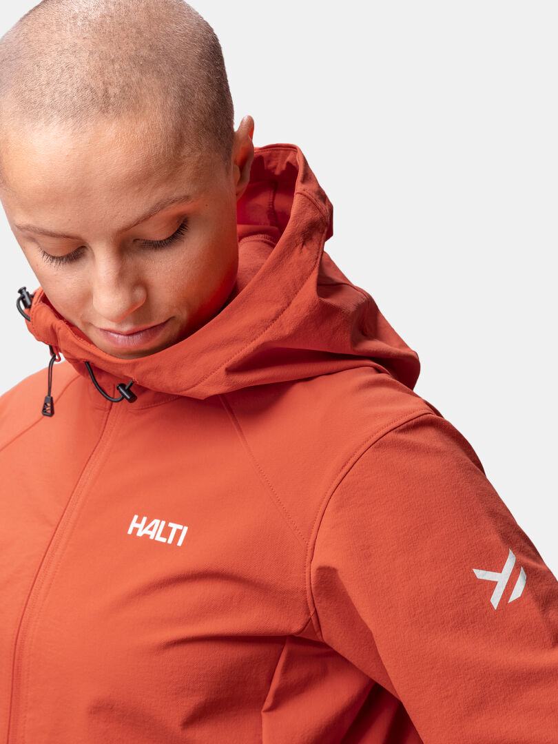 A woman in a Halti Finholma X-stretch Jacket with hood looks down; the jacket is lightweight and water-repellent.
